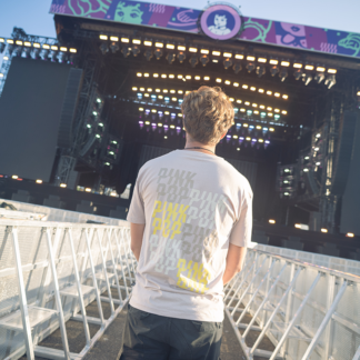 Man met bruin shirt. Kleine Pinkpop-logo's op achterkant shirt in kleuren beige, bruin en geel.