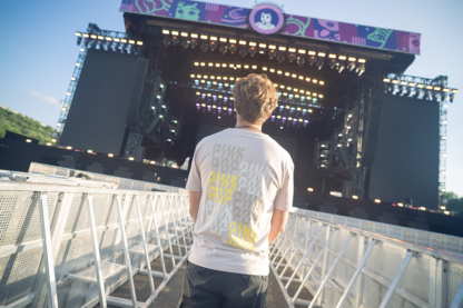 Man met bruin shirt. Kleine Pinkpop-logo's op achterkant shirt in kleuren beige, bruin en geel.