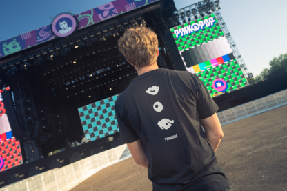 Man met zwart shirt met signature Pinkpop-oogje, knoopje en mondje op rug gedrukt