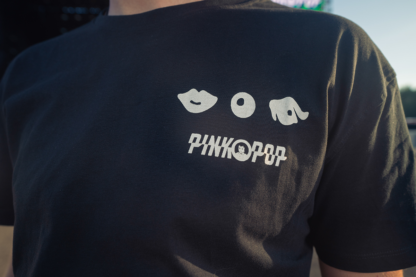 Zwart shirt met signature Pinkpop-oogje, knoopje en mondje op linker borst gedrukt.