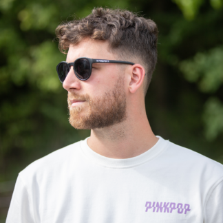 Man met zwarte zonnebril met wit Pinkpop-logo op zijkant oortje.